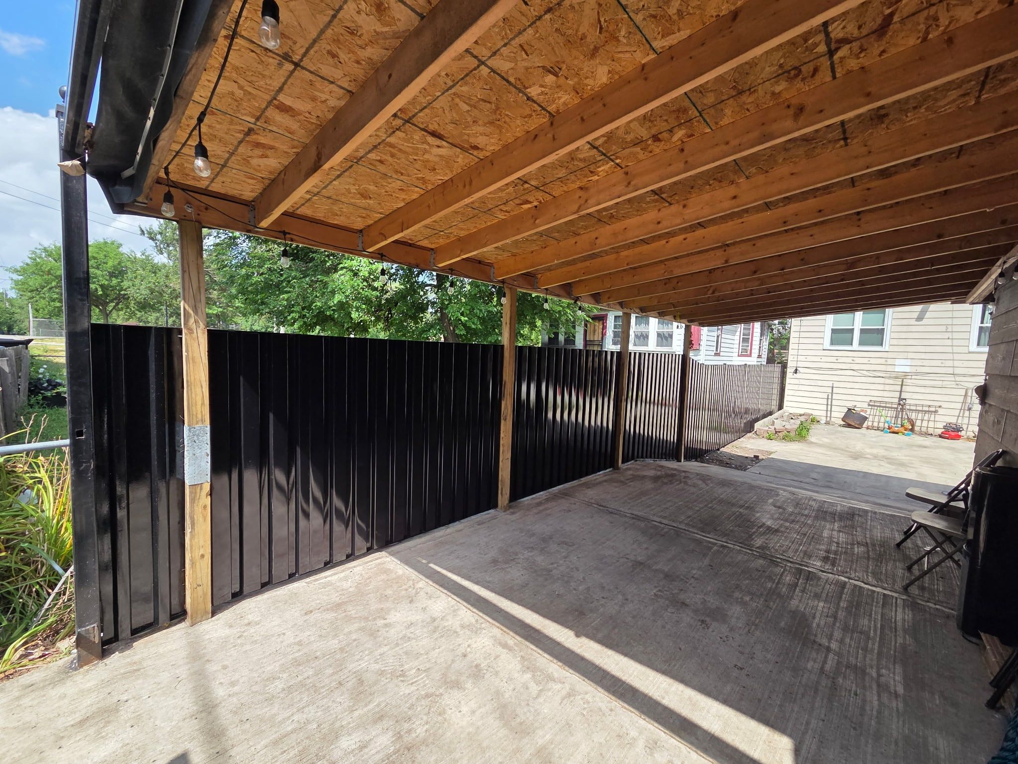 Black steel privacy fence seen from a covered patio in the backyard