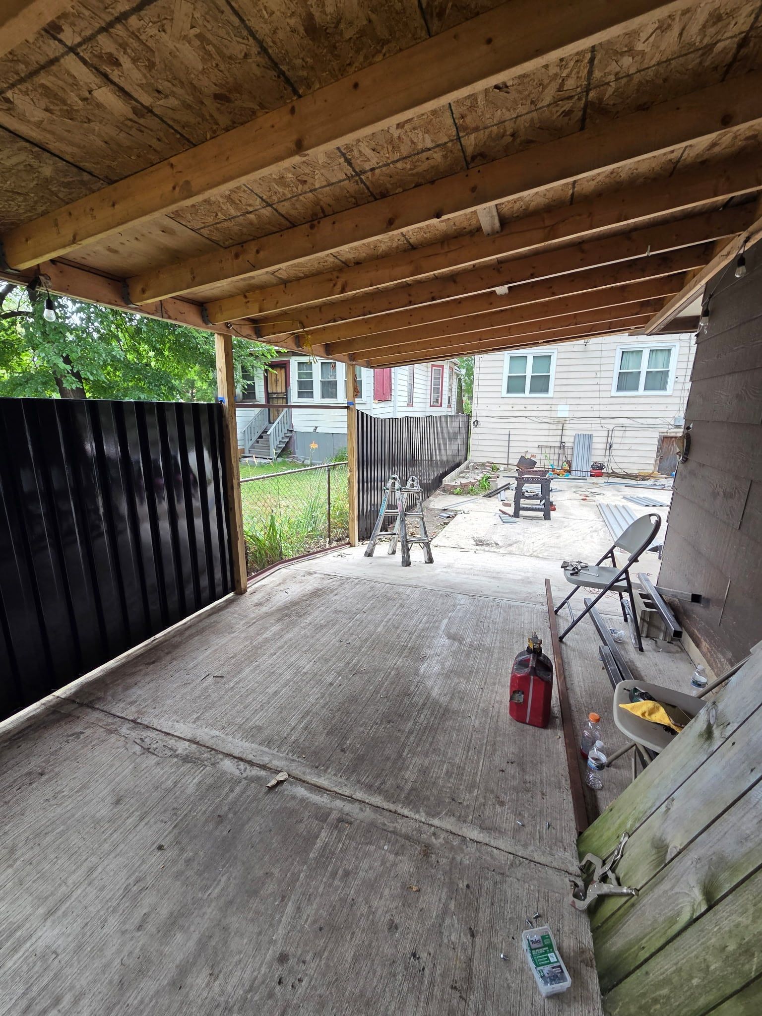 The black steel fence enclosing the yard, viewed from under the covered area