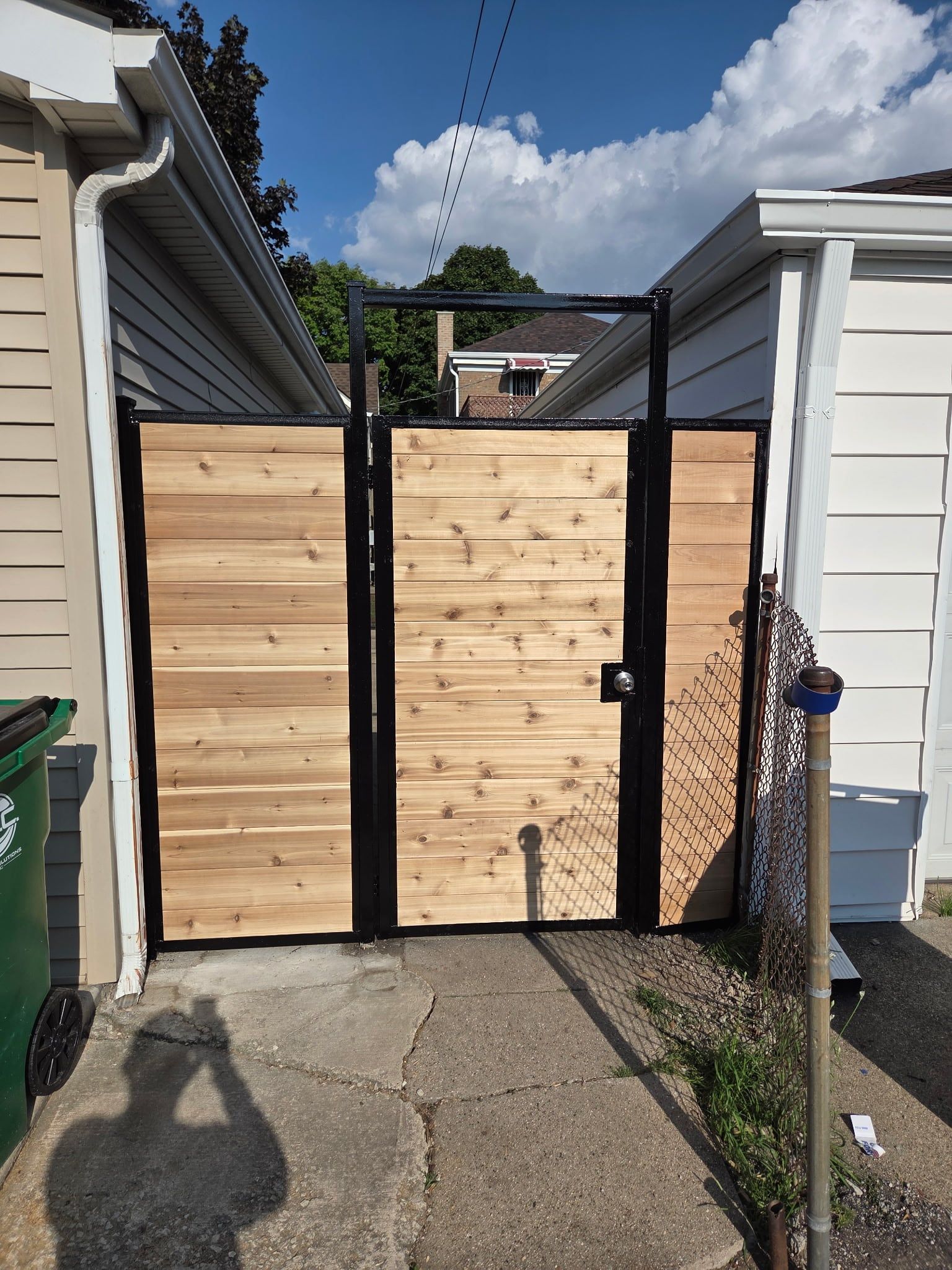 New cedar walk gate in a black steel frame between the house and the garage