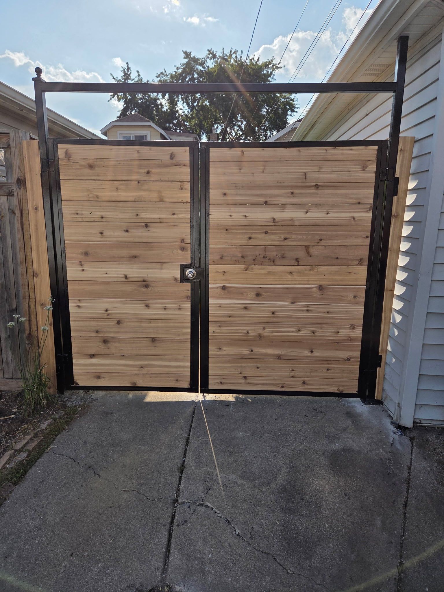 Double cedar gate in a black steel frame with an overhead steel header