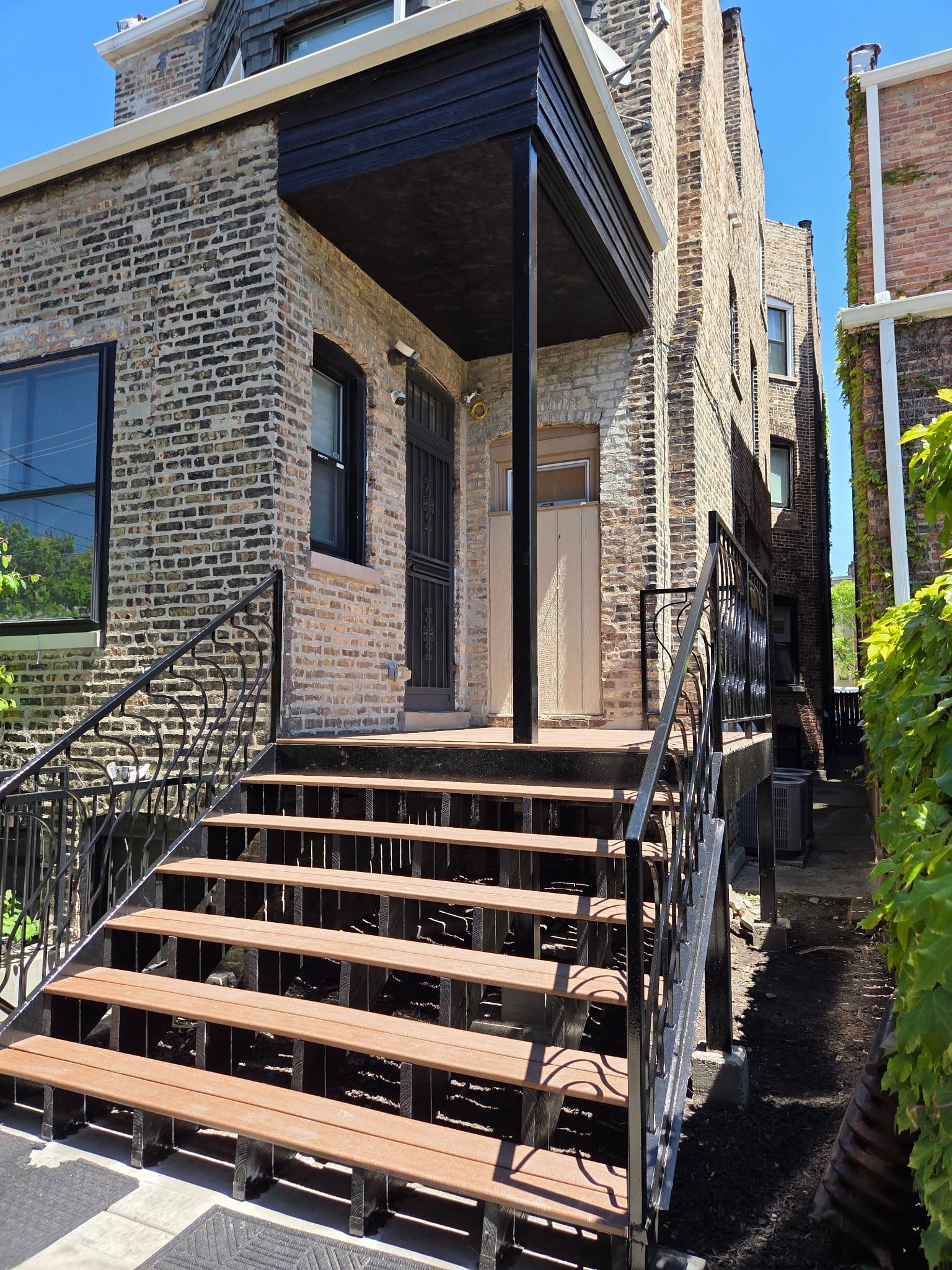 Front steps of a brick two-flat with black ornamental iron railings on both sides