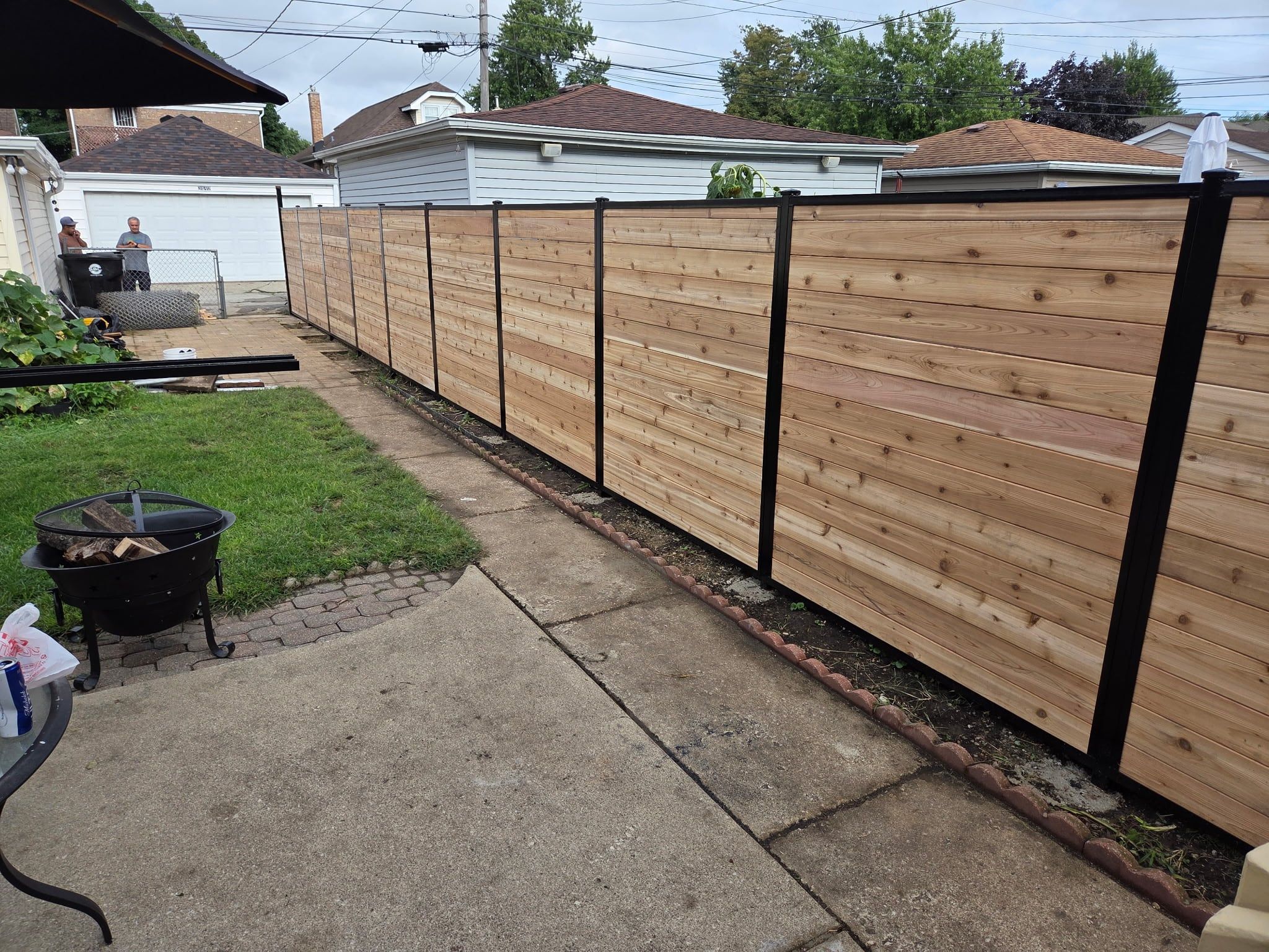 The same cedar fence seen from the other end of the yard, running toward the garage