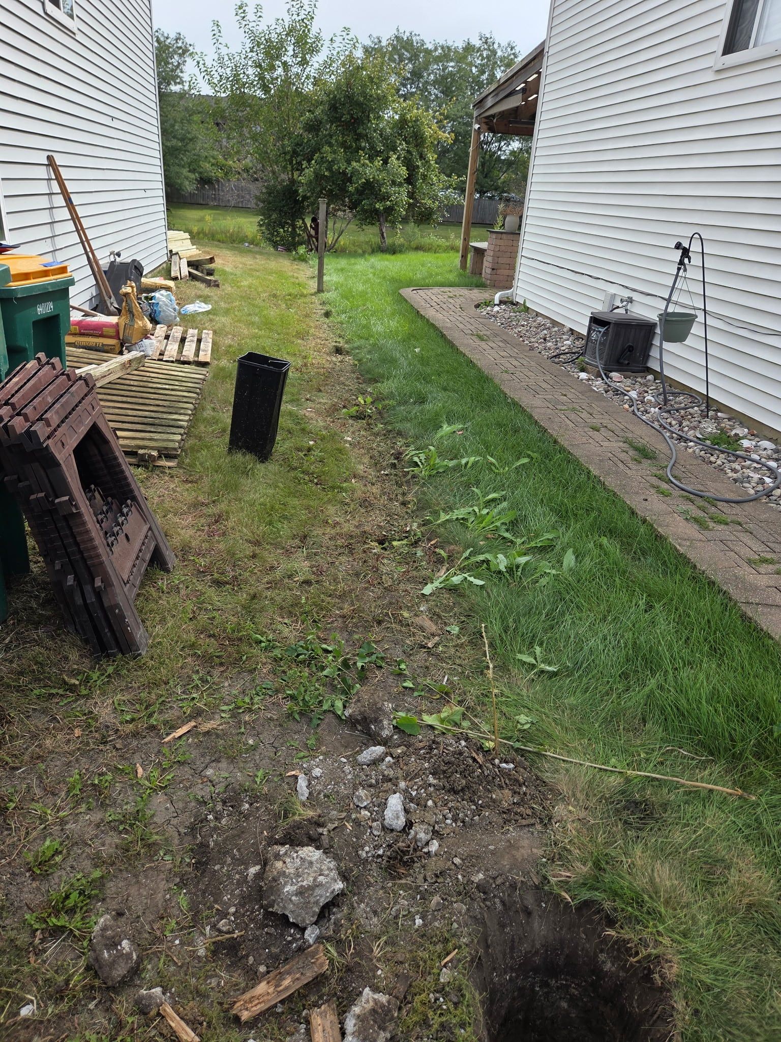 Side yard before the new fence, with debris and the first post hole dug