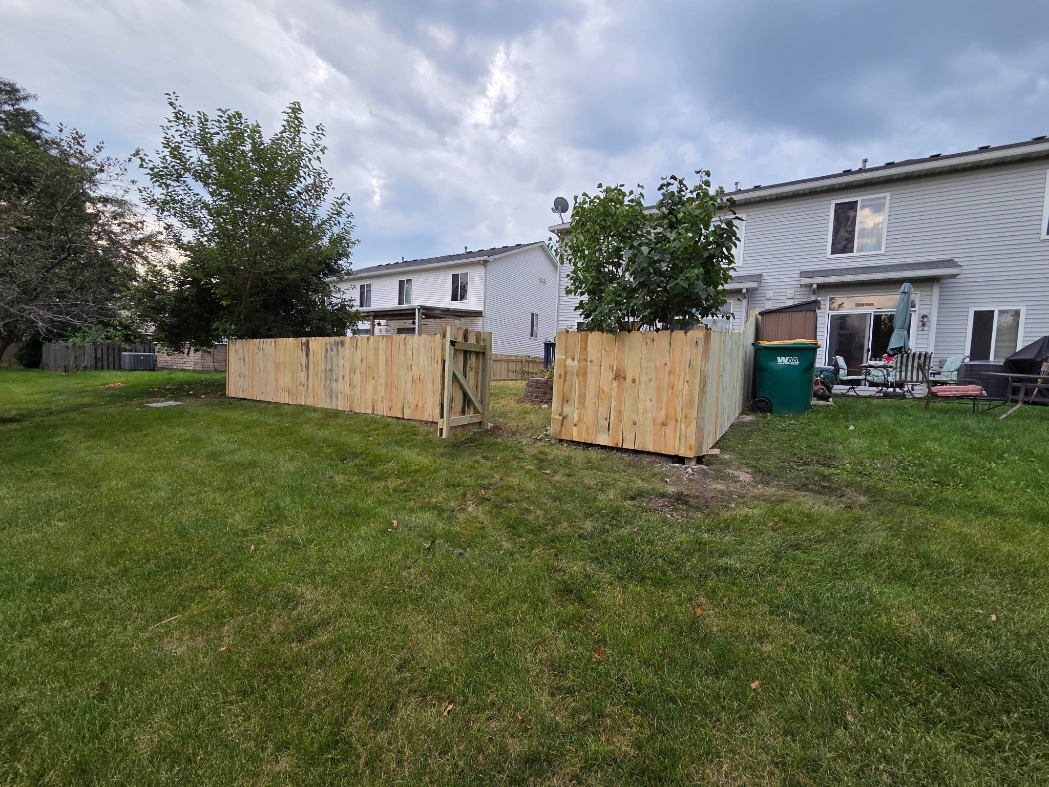 New wood privacy fence with a walk gate around a backyard